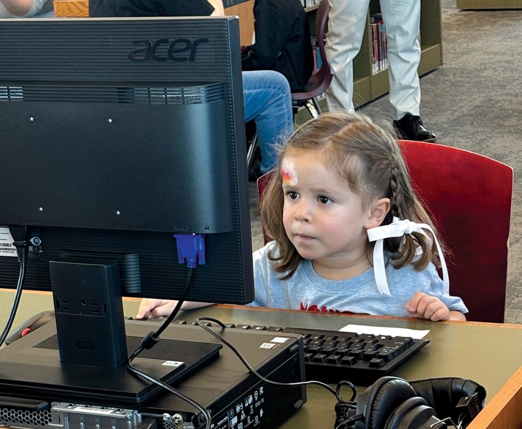 Little girl at computer inside library