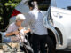 caregiver helping disabled elderly woman in wheelchair to get into the car