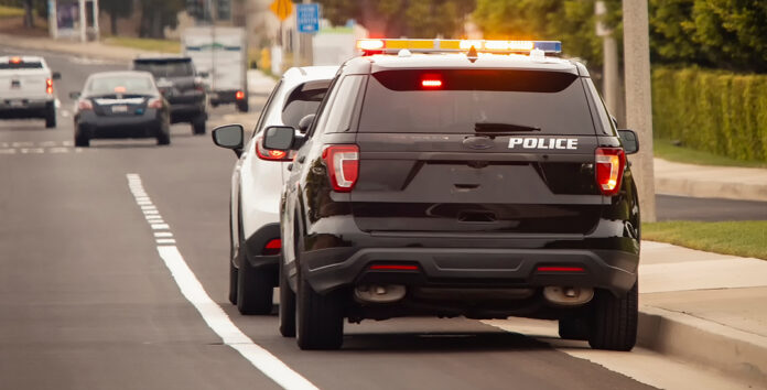 Police car traffic AdobeStock_1221489023 Behind view of a police car that pulled a motorist over to the side of the road